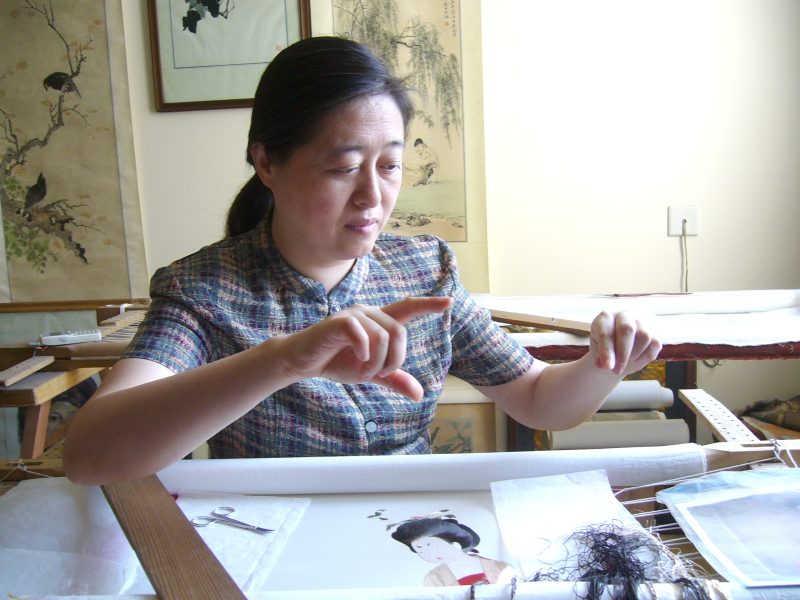 Xiaocheng Shao working with thread at a traditional embroidery frame