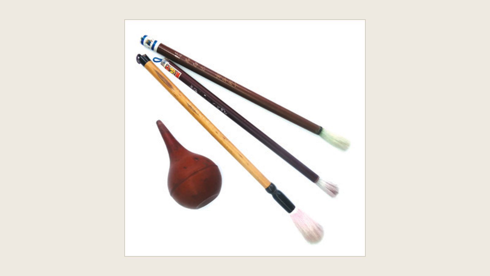 Traditional soft brushes and a rubber air blower used for removing dust from embroidery