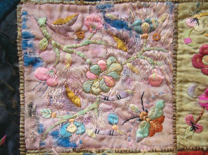 Close view of an aged embroidered surface with weakened and loose threads