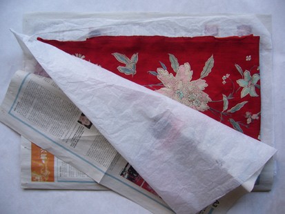 Embroidery covered with white paper and newspaper for flat storage