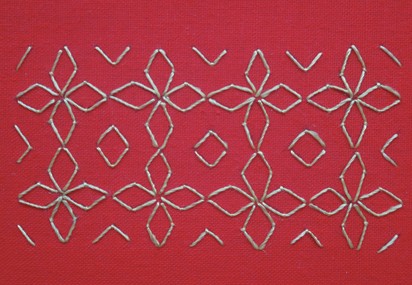 A completed net-stitch pattern in light thread on red fabric
