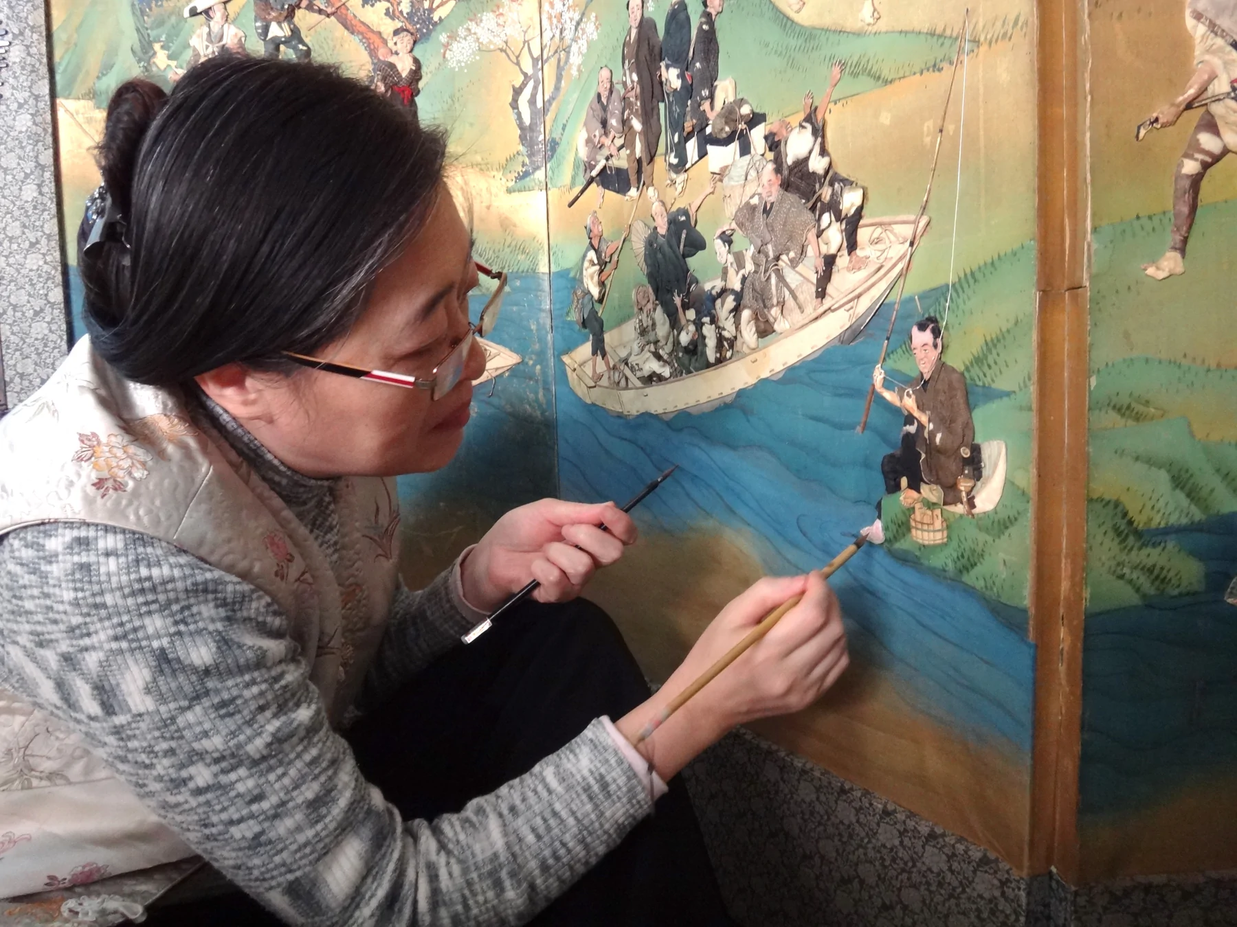Shao Xiaocheng carrying out conservation treatment on a Japanese raised-embroidery screen