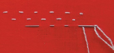 Short light stitches arranged on red fabric