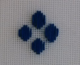 Four dark-blue counted-stitch blocks worked on a visible gauze grid