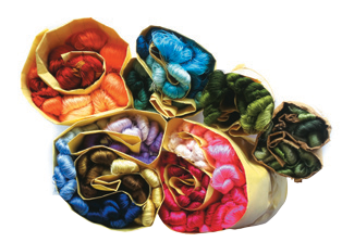 Folded paper packets holding bundles of coloured embroidery threads.