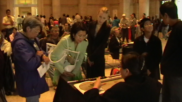 Visitors gathered around an embroidery hoop and textile work in a 2008 San Francisco archive photograph.