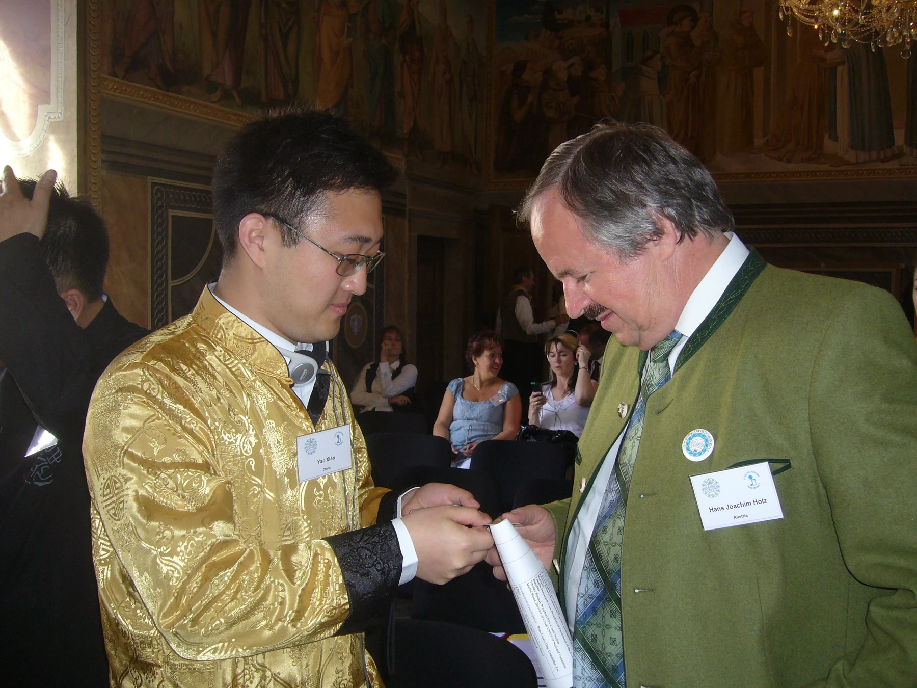 Yao Xiao and another IOV-badged attendee examining a printed document in Prague, April 2012.