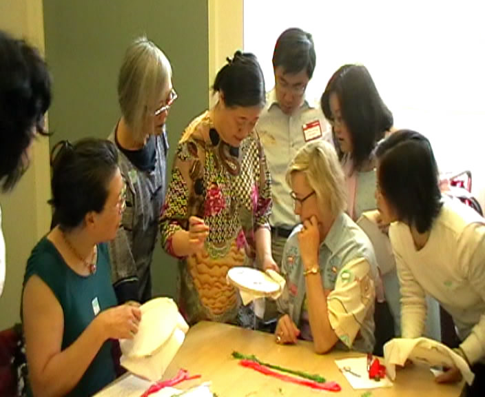 Participants gather around an embroidery hoop during a Chinese embroidery teaching session, from the Institute’s 2008 San Francisco archive.